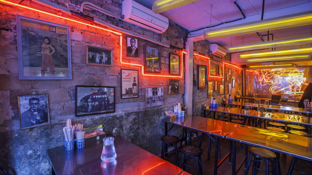Photo de l'intérieur du restaurant Street Bangkok roast club à Etienne Marcelle décoré avec néon et cadres photos sur mur en pierre